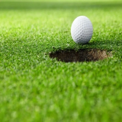 Golf ball near hole on green field showing how 18 holes became the global standard in golf.